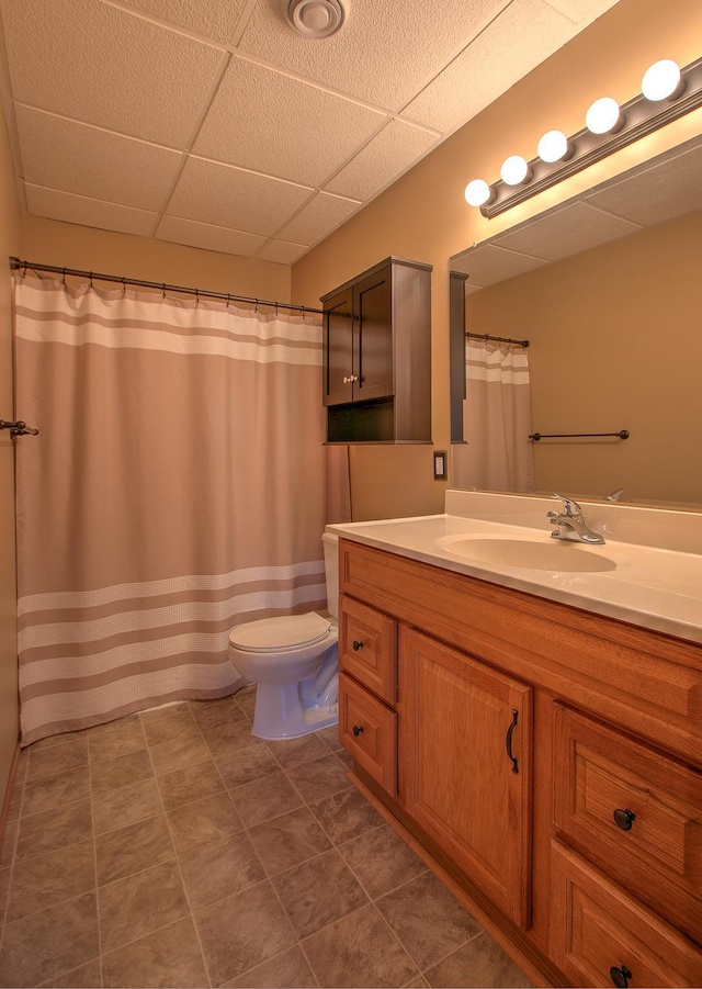 full bath featuring vanity, tile patterned flooring, a drop ceiling, and toilet
