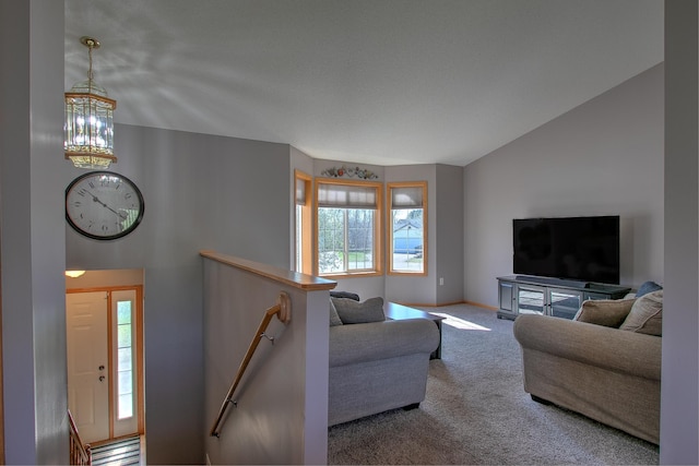 carpeted living area with baseboards, a notable chandelier, and lofted ceiling