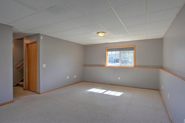 spare room featuring baseboards, carpet flooring, a paneled ceiling, and stairs