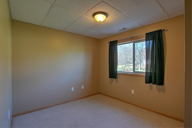 carpeted spare room featuring baseboards, a paneled ceiling, and visible vents