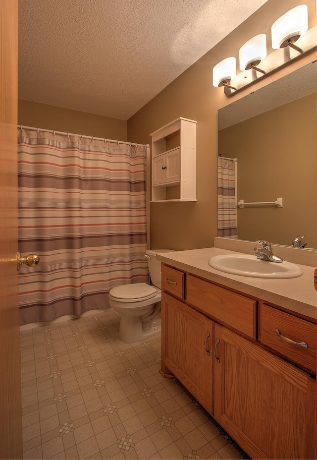 bathroom with vanity, toilet, a textured ceiling, tile patterned floors, and a shower with curtain