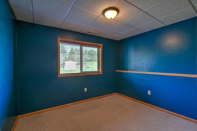 unfurnished room featuring baseboards, visible vents, a drop ceiling, and carpet