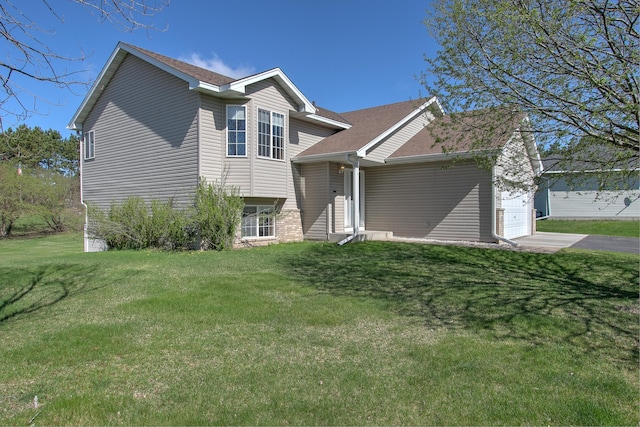 tri-level home with driveway, a shingled roof, a front lawn, and a garage