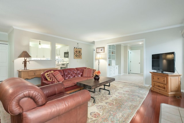living room with ornamental molding, light wood-style flooring, and baseboards