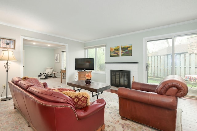 living room with ornamental molding, a fireplace, light wood-style flooring, and baseboards