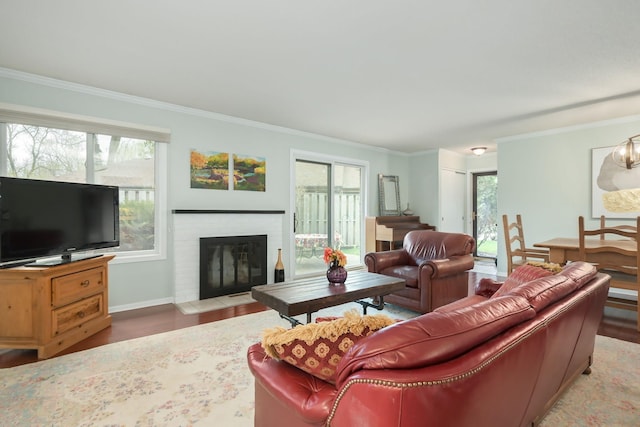 living room with wood finished floors, ornamental molding, a brick fireplace, and baseboards