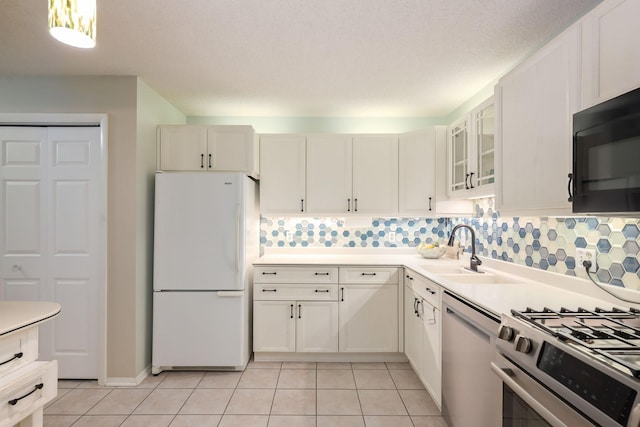 kitchen with freestanding refrigerator, a sink, black microwave, dishwashing machine, and stainless steel range with gas cooktop