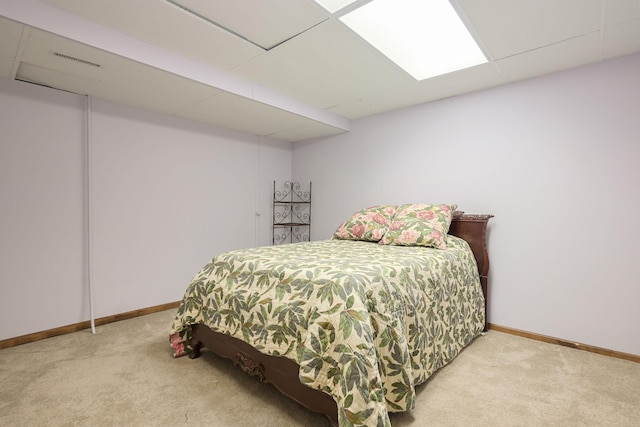 carpeted bedroom featuring baseboards and a drop ceiling