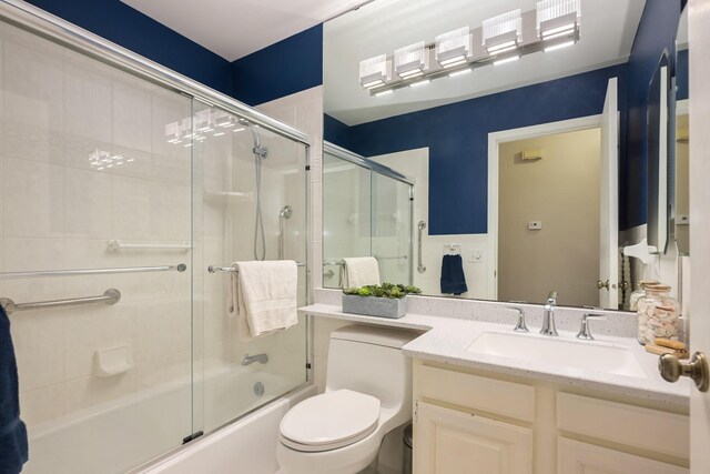full bath featuring combined bath / shower with glass door, vanity, and toilet