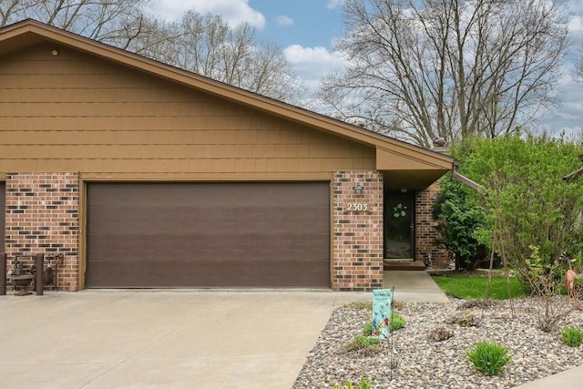 view of side of home featuring brick siding, concrete driveway, and an attached garage
