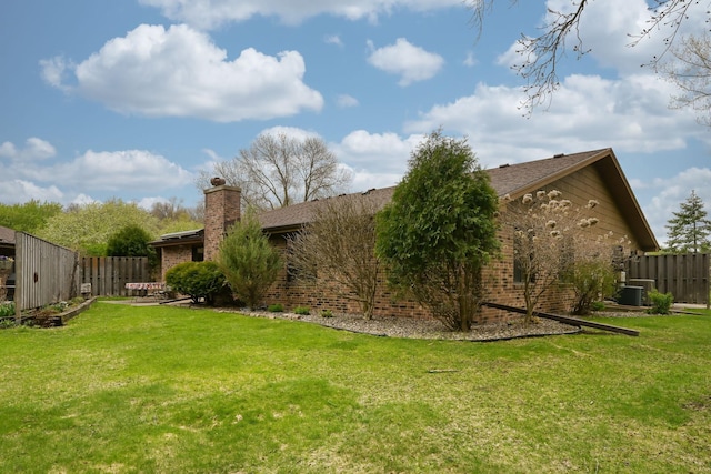 view of side of property with a chimney, brick siding, and cooling unit