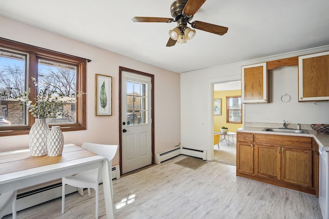 kitchen featuring a sink, a wealth of natural light, brown cabinetry, and a baseboard radiator