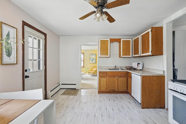 kitchen with brown cabinets, a sink, a healthy amount of sunlight, light countertops, and white appliances