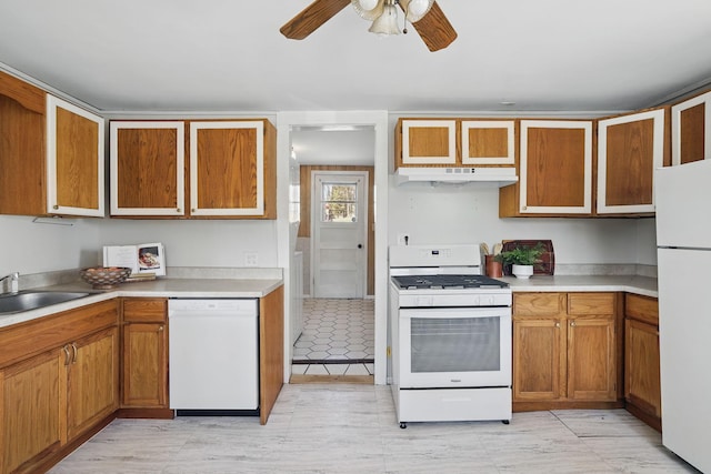 kitchen featuring white appliances, brown cabinetry, under cabinet range hood, light countertops, and ceiling fan