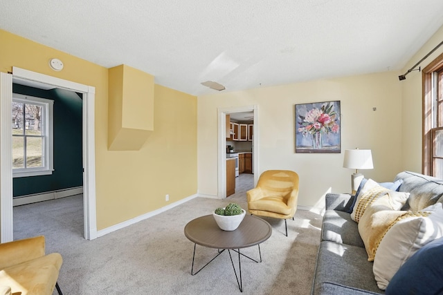 living room with baseboard heating, baseboards, light colored carpet, and plenty of natural light