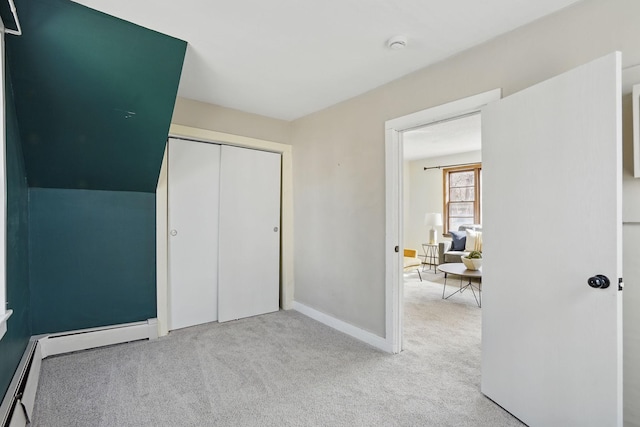 unfurnished bedroom with baseboards, carpet floors, a closet, and a baseboard radiator