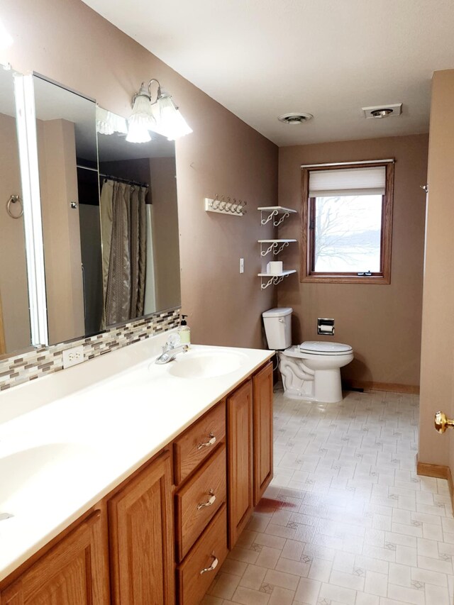 bathroom with double vanity, toilet, visible vents, and a sink