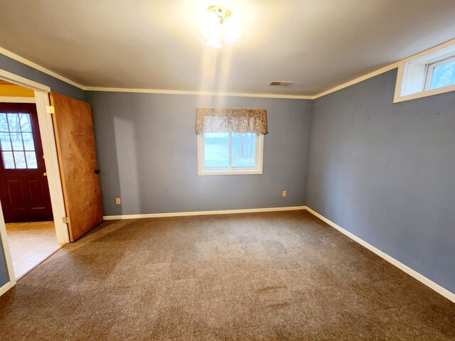 carpeted spare room featuring crown molding, visible vents, and plenty of natural light