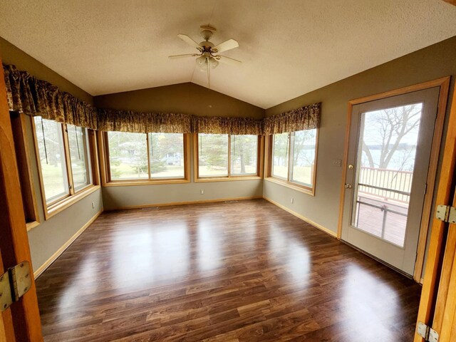unfurnished sunroom featuring baseboards, a textured ceiling, wood finished floors, and lofted ceiling