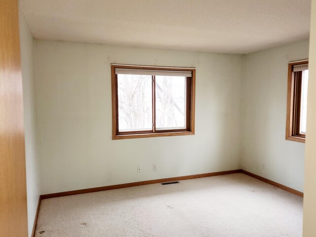 carpeted empty room with baseboards and visible vents