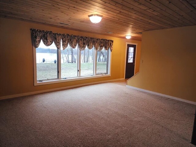 carpeted spare room featuring baseboards, visible vents, and wooden ceiling