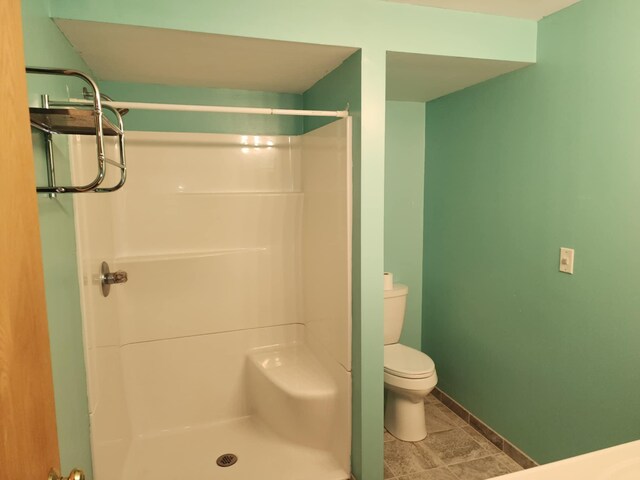full bathroom with baseboards, tile patterned floors, a shower stall, and toilet
