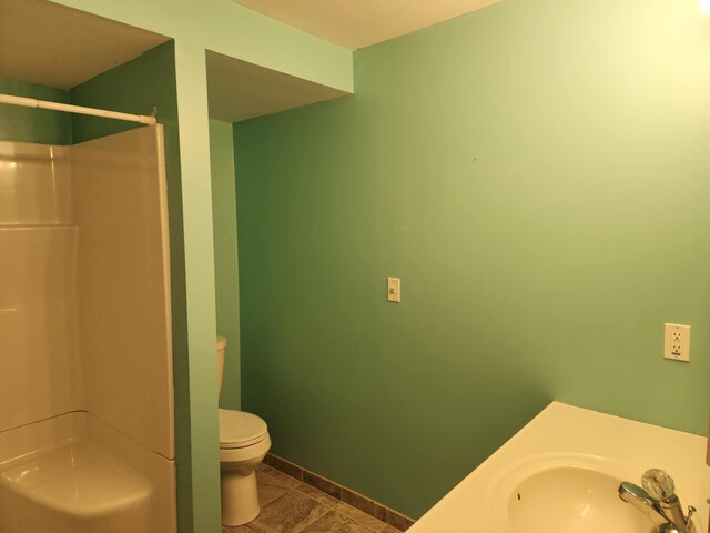 full bath featuring baseboards, a sink, a stall shower, and toilet