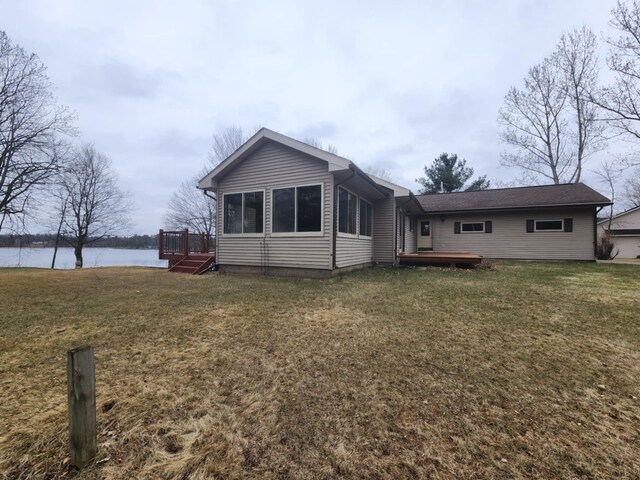 back of house featuring a deck with water view and a lawn