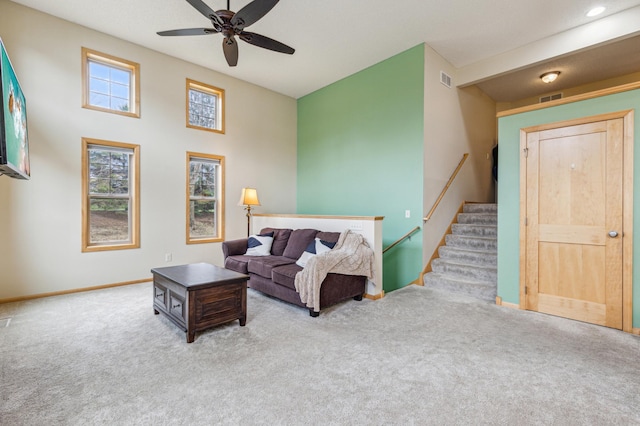 living area featuring carpet floors, stairs, a ceiling fan, baseboards, and visible vents