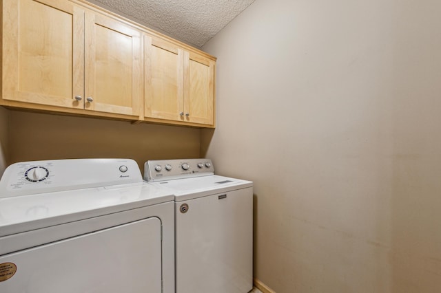 washroom with washer and clothes dryer, cabinet space, and a textured ceiling