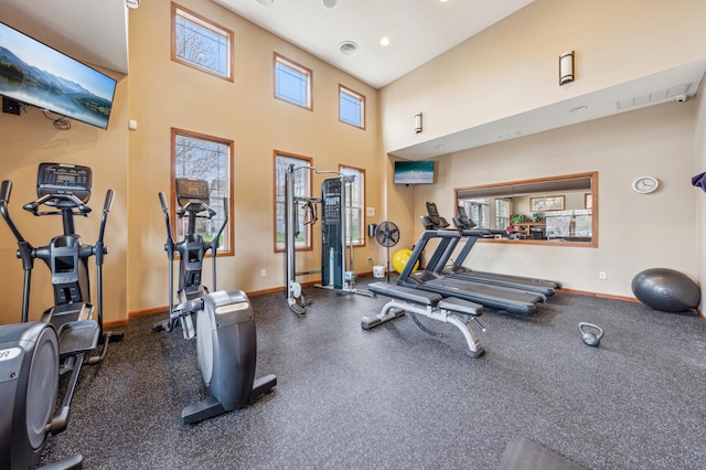 workout area with recessed lighting, baseboards, and a high ceiling