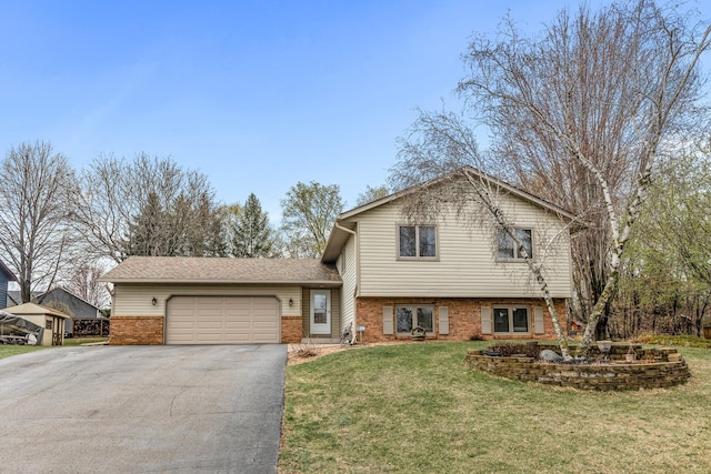 tri-level home with an attached garage, a front yard, aphalt driveway, and brick siding