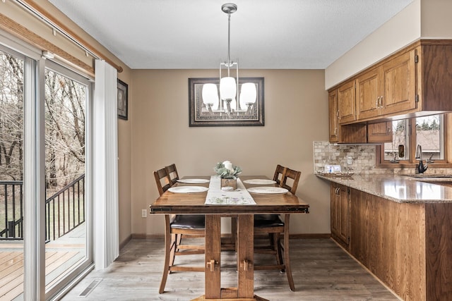 dining space with baseboards, an inviting chandelier, light wood-style flooring, and visible vents