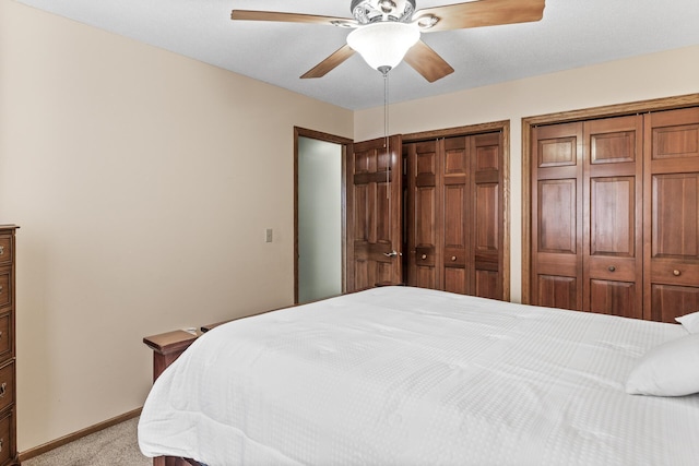 bedroom featuring baseboards, a ceiling fan, multiple closets, and light colored carpet