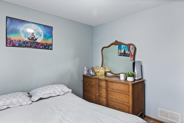 bedroom featuring visible vents, a textured ceiling, and baseboards