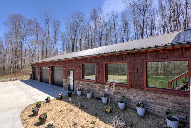 546 315th St, Cady Twp, WI 54749 - view of side of home featuring a garage, driveway, stone siding, and metal roof