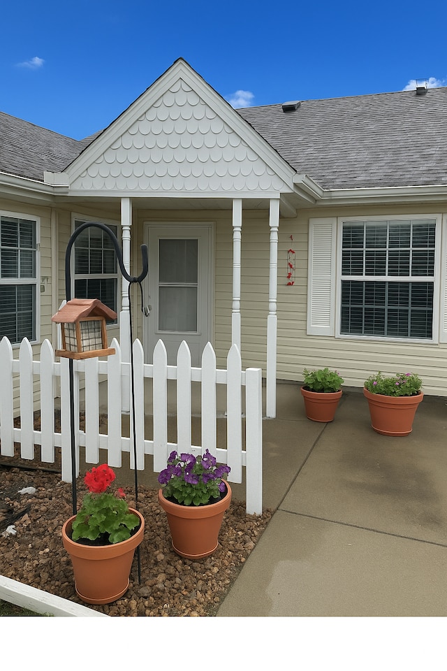 property entrance with covered porch and roof with shingles