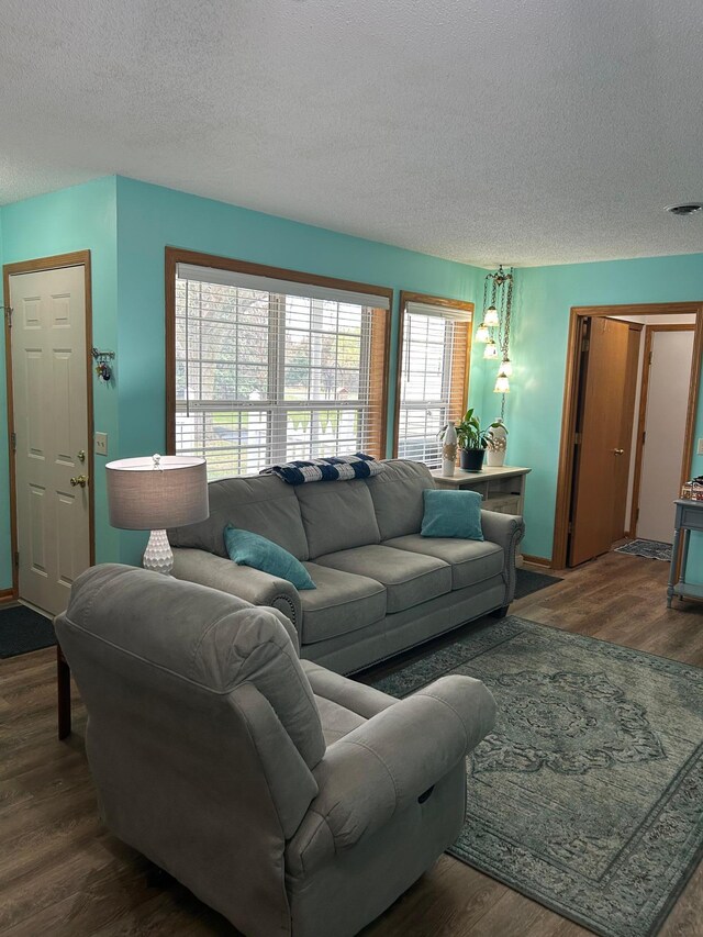 living area with baseboards, a textured ceiling, visible vents, and wood finished floors
