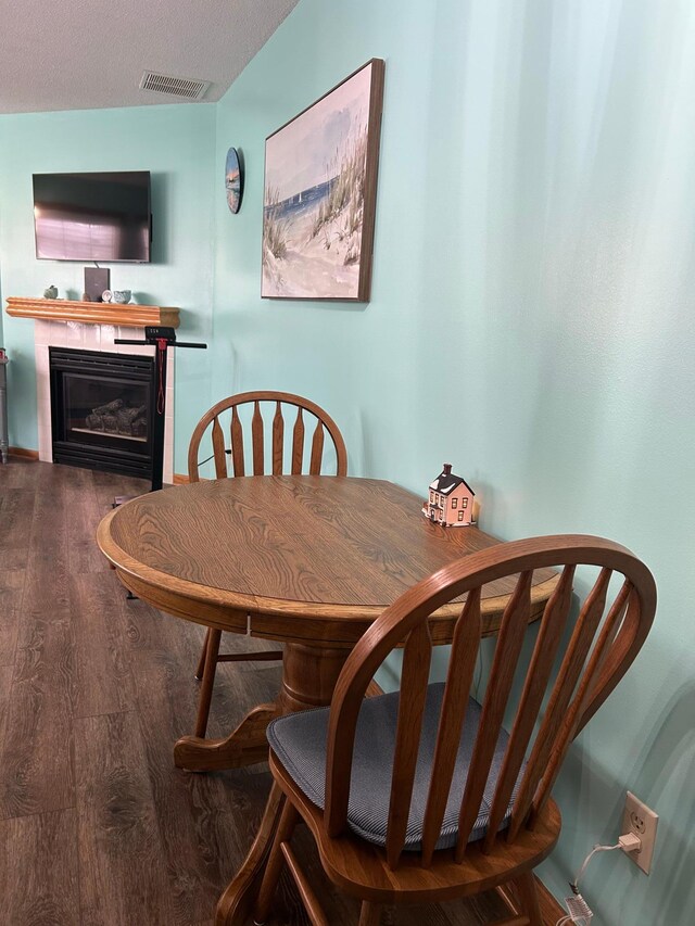 dining room featuring a glass covered fireplace, wood finished floors, and visible vents