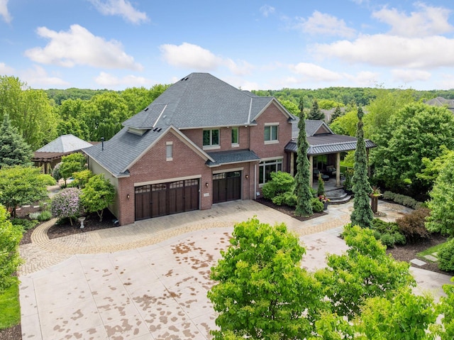7250 Jubert Ln, Corcoran, MN 55340 - view of front facade with an attached garage, decorative driveway, roof with shingles, brick siding, and a view of trees