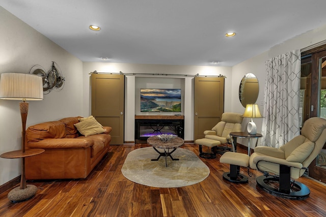 living room featuring a barn door, wood finished floors, recessed lighting, and baseboards