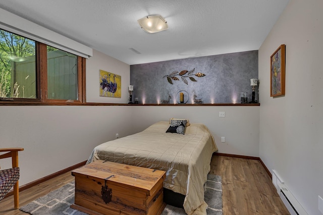 bedroom with wood finished floors, a baseboard radiator, and baseboards