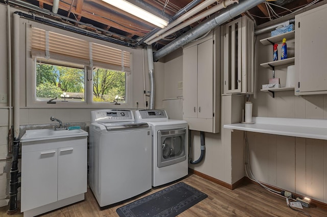 clothes washing area featuring independent washer and dryer, cabinet space, and light wood finished floors