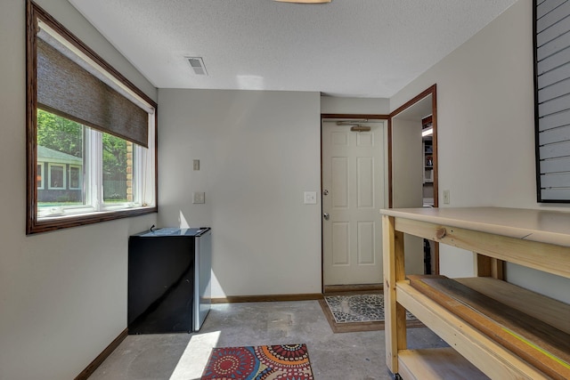 entryway with baseboards, a textured ceiling, and unfinished concrete floors