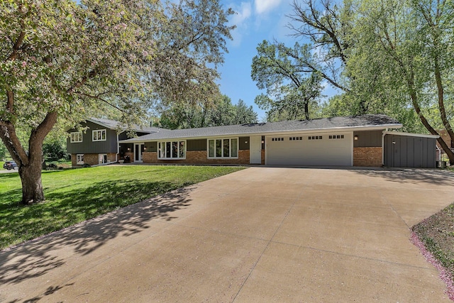 split level home with brick siding, an attached garage, concrete driveway, and a front lawn