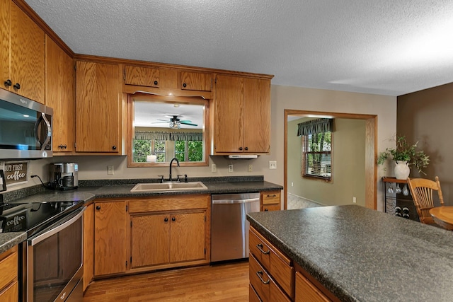 1410 4th Ave N, Sartell, MN 56377 - kitchen with stainless steel appliances, a sink, dark countertops, light wood finished floors, and a textured ceiling