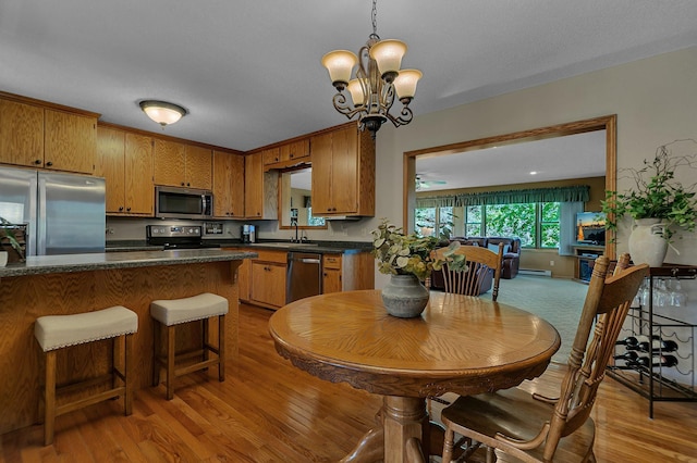 1410 4th Ave N, Sartell, MN 56377 - kitchen featuring stainless steel appliances, dark countertops, brown cabinets, and light wood-style flooring