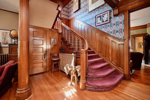 265 Broadway St, Winona, MN 55987 - stairs with wainscoting, wood finished floors, wallpapered walls, decorative columns, and ornamental molding