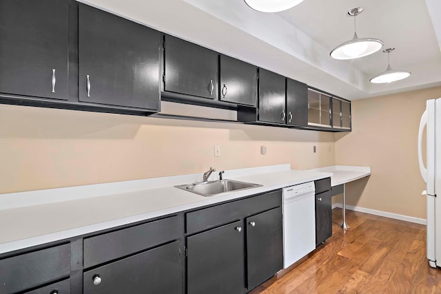 kitchen with a sink, white appliances, light wood-type flooring, light countertops, and baseboards