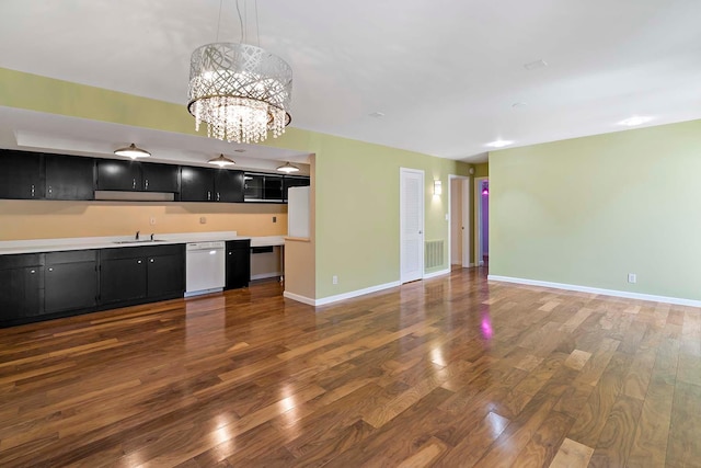 kitchen with dark cabinets, dishwasher, a sink, dark wood-type flooring, and a chandelier